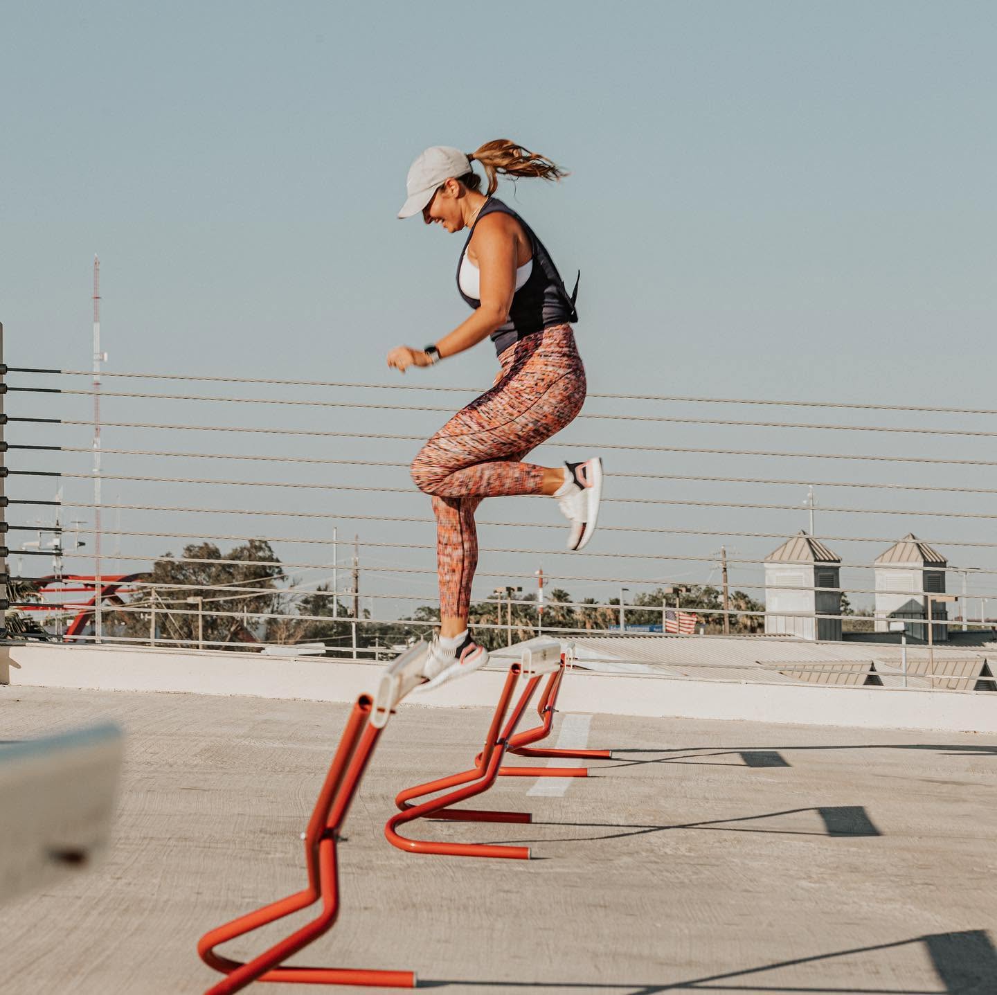 A Cardio Blast member clearing agility hurdles mid-air on the downtown Brownsville rooftop during Sunday small group training