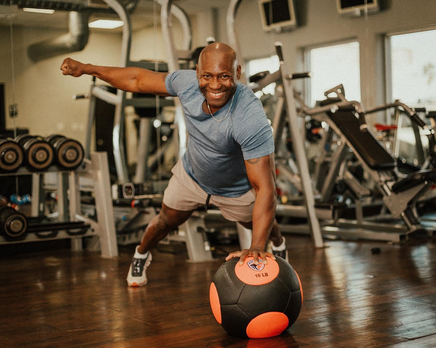 Alex Ampadu balancing one-handed on a medicine ball at the 101 Fitness studio in Brownsville — his own method of movement in action