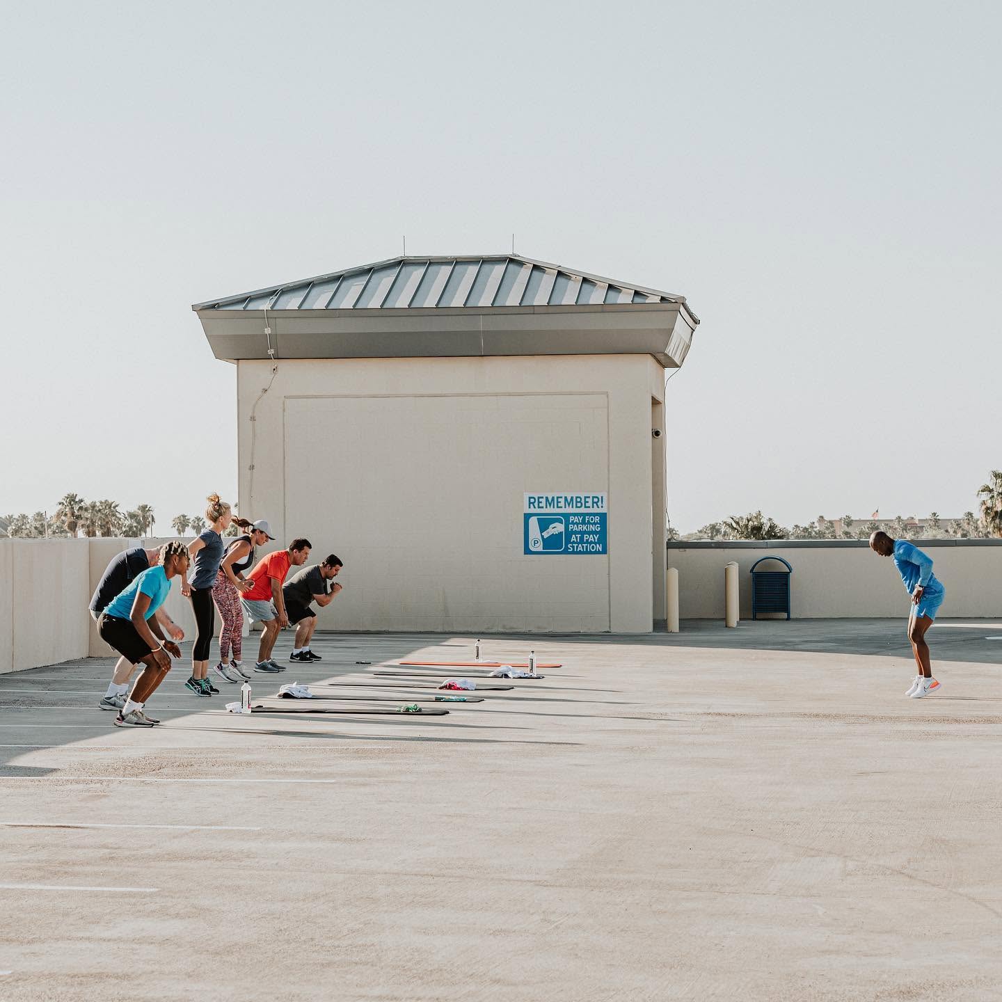 The Cardio Blast crew squatting in unison as Alex leads a Sunday session on the downtown Brownsville parking garage rooftop