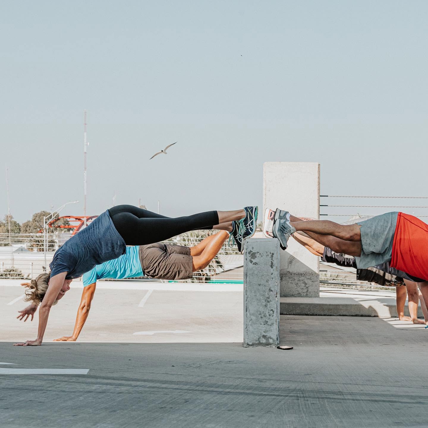 Partner plank drills with feet on the concrete ledges during an outdoor Cardio Blast workout in downtown Brownsville